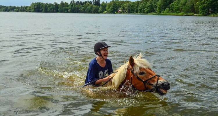 A rider swimming in water with a horse